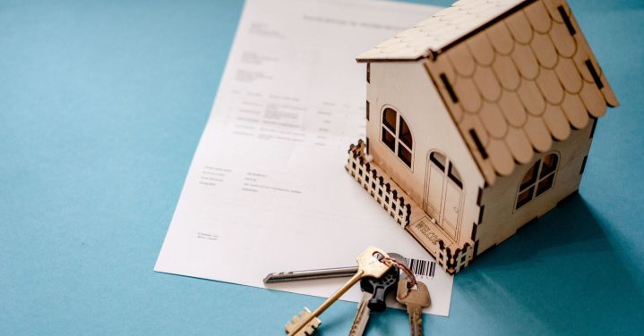 Fraude à execução de imóvel: chaves e contrato ao lado de uma casa em miniatura na compra de um imóvel